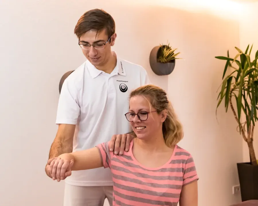 Therapeut prüft die Schulterbeweglichkeit einer Patientin