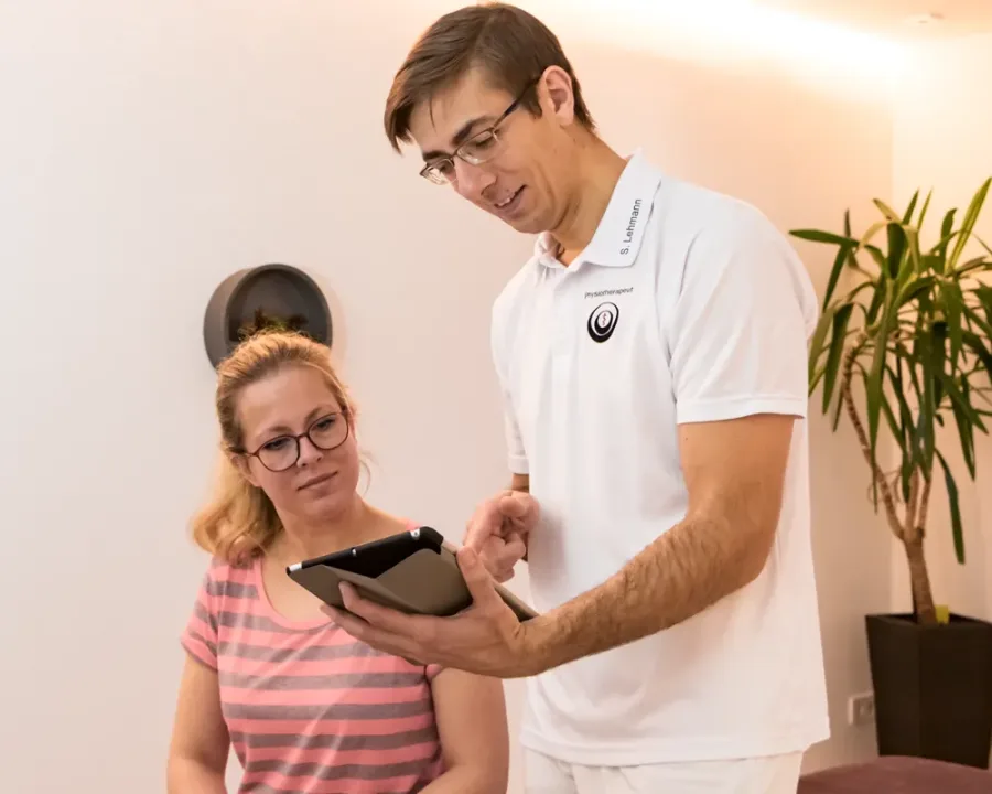 Physiotherapeut bespricht mit einer Patientin den Befund am Tablet